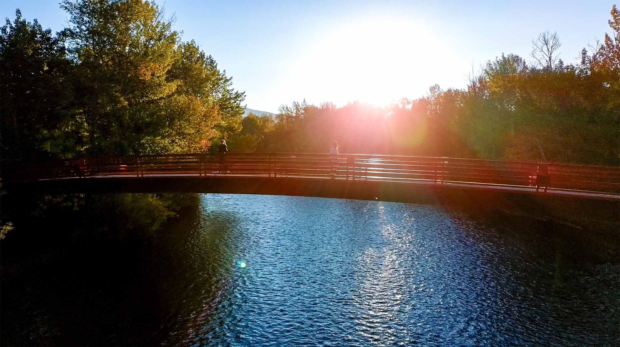 Aerial view of the Friendship Bridge glowing in the morning light, spanning the Boise River with trees and trails on either side — a quiet moment that captures the city’s warmth and clarity.