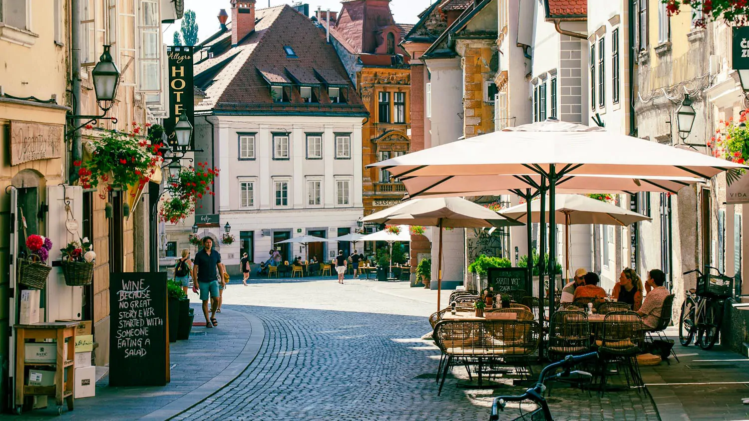 Pedestrian street with outdoor café seating and historic buildings in a European town square.