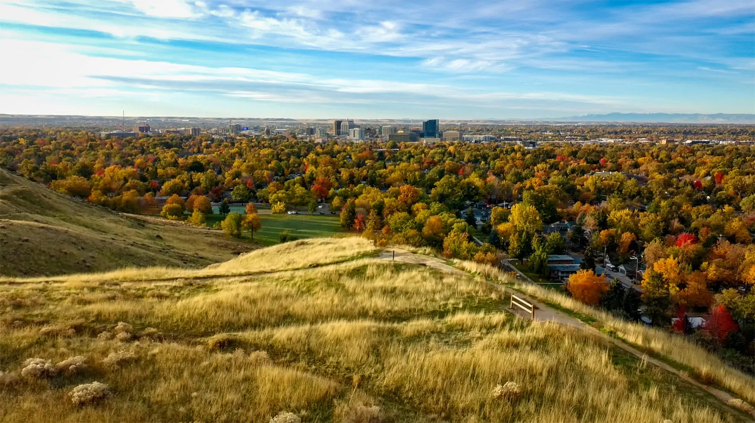 View from the Boise foothills showing a dirt trail in the foreground and the city below in autumn