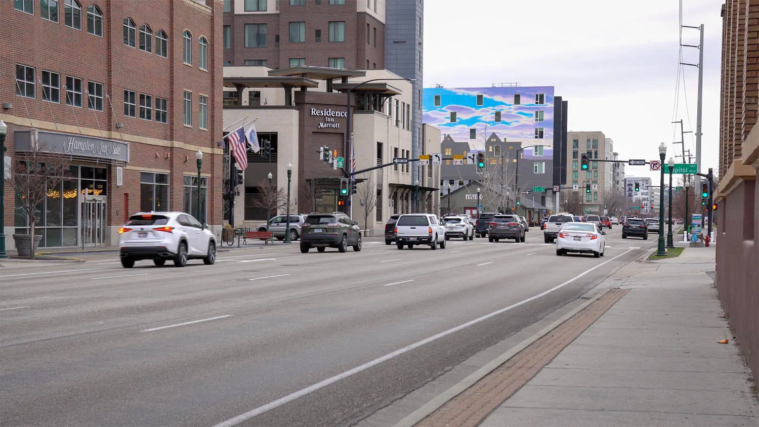 Downtown Boise street scene with wide traffic lanes, sidewalks, signals, and brick buildings near 8th Street.